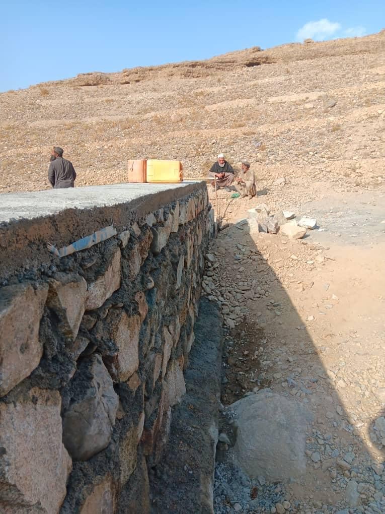 Workers constructing a stone retaining wall in rural Afghanistan